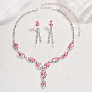 Detail of silver bridal necklace and pink marquise earrings on white silk fabric