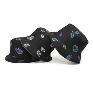 Détail de bobs en coton avec imprimés papillons en couleurs violette, blanche et bleue