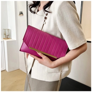 Detail of rose red pleated clutch bag featuring metallic trim and chain strap