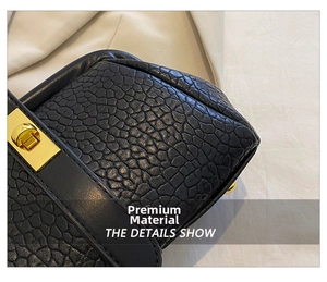Close-up of black lychee grain leather handbag with rectangular gold metal twist lock