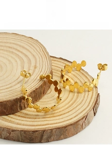 Macro shot of gold-plated stainless steel bubble earrings on a rustic wood slice