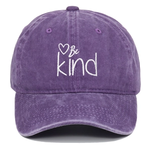 Detailed close-up of Be Kind heart embroidery on vintage washed purple cotton baseball cap