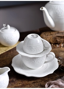 Detail showing vintage embossed floral patterns on white ceramic teapot and coffee cup