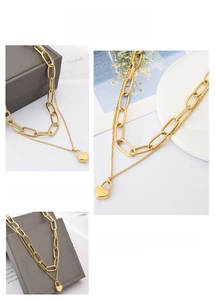 Detail view of double layer gold stainless steel chain necklace with heart lock pendant