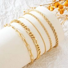 Détail de cinq bracelets à chaîne plaqués or 14 carats présentés sur rouleau blanc