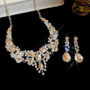 Detailed view of sparkling teardrop rhinestone necklace and earring set on black background