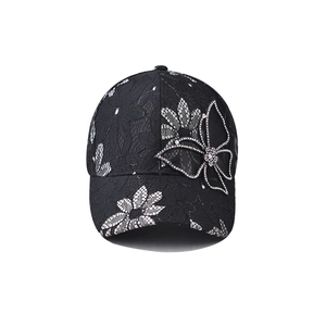 Detail of elegant black lace baseball cap with butterfly rhinestone and floral embroidery