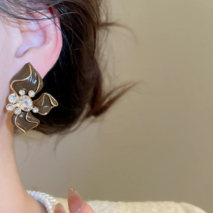 Close-up of coffee-colored floral stud earrings with gold edges and crystal details