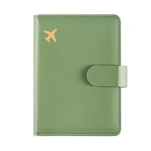 Porta passaporto in pelle verde con icona aereo dorata e chiusura a scatto su fondo bianco