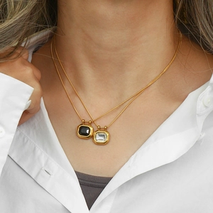 Detailed view of a layered 18K gold-plated lock pendant necklace worn on a model