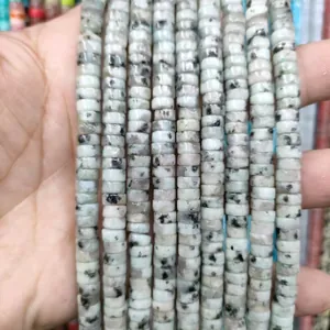 Close-up of flat disc-shaped natural green stone beads with black spots for DIY jewelry