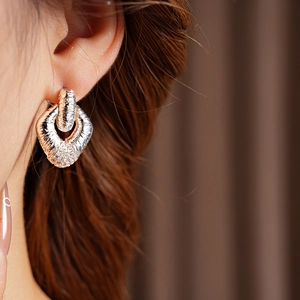 Detail of rose gold textured geometric earrings with shimmering pavé crystal settings