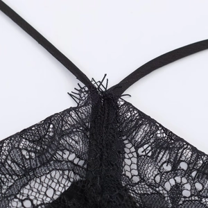 Detail of delicate black eyelash lace trim and thin shoulder strap on satin dress