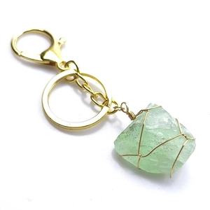 Détail d'un porte-clés artisanal en pierre naturelle verte enveloppé de fil doré