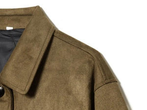 Makrodetail der olivefarbenen Wildlederjacke mit Kragen, Schultertextur und schwarzem Knopf