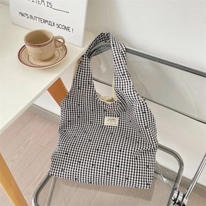 Close-up of black and white checkered canvas tote bag with floral print on an acrylic chair