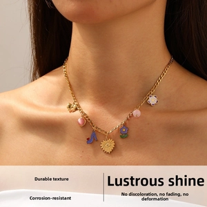 Close-up of gold Figaro necklace with colorful enamel charms on model's neck