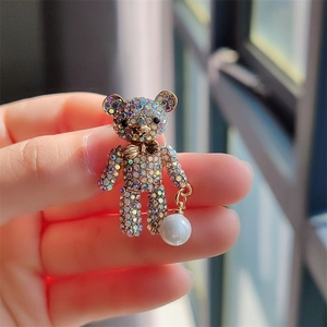 Detailed close-up of a golden bear brooch set with colorful rhinestones and a white pearl