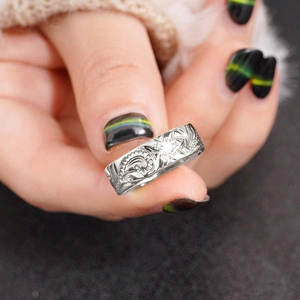 Close-up of wide silver ring with intricate embossed floral texture and vintage details