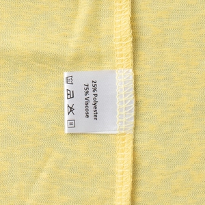 Detail of yellow knit fabric showing washing label with 75% viscose and 25% polyester