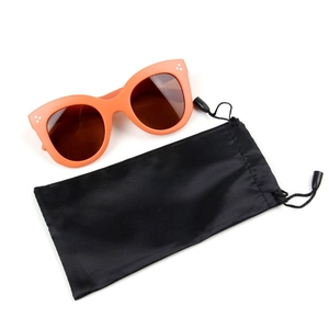 Detail of orange oversized sunglasses with three dot accents and a black drawstring pouch