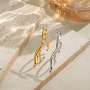 Minimalist gold and silver curved rings shown on travertine stone in natural sunlight