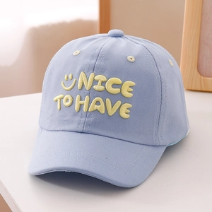 Close-up of blue kids baseball cap with yellow smiley face and NICE TO HAVE embroidery