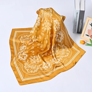 Detail of mustard yellow silk square scarf with white paisley and floral patterns