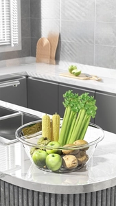 Close-up of a large transparent basin holding fresh vegetables on a modern marble countertop