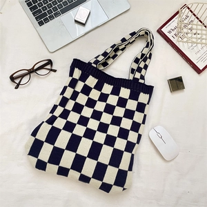 Flat lay of knit checkerboard tote bag with laptop and glasses on textured background