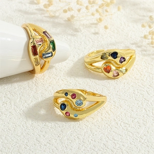 Detailed view of three gold rings with multi-colored gemstones on a textured surface