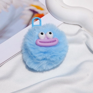 Detail of blue fuzzy monster keychain with purple lips on soft white fabric