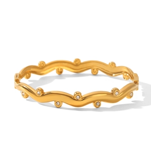 Detailed close-up of wavy gold-plated bangle with sparkling white zircon stones