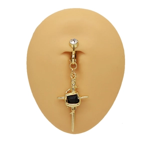 Macro detail of golden cross belly ring with black gem and white rhinestone accents