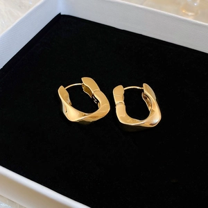 Macro shot of gold irregular U-shaped hoop earrings resting in a jewelry gift box
