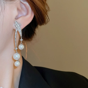 Gros plan de boucles d'oreilles météore avec perles blanches et strass sur un mannequin