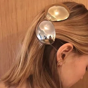 Macro detail of metallic eggshell hair clip and gold ear cuff on a model's hair
