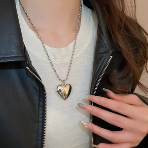 Polished silver heart pendant on a bead chain necklace worn with a black leather jacket
