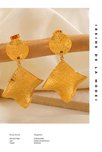 Macro shot of gold geometric earrings with irregular wavy edges on a rustic wood branch