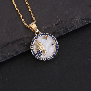 Macro view of 18K gold Capricorn pendant with white shell inlay and blue gemstones