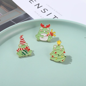 Detailed view of three cute Christmas frog enamel pins with festive holiday motifs