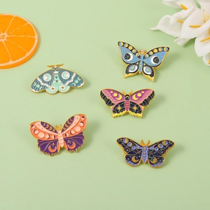 Detailed flat lay of five colorful enamel butterfly brooches with celestial moon patterns