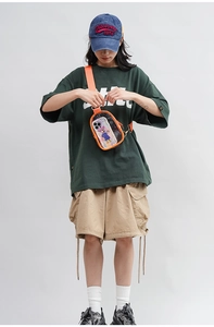 Detailed view of clear PVC crossbody bag with orange trim worn by a model