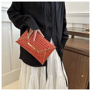 Elegant red envelope clutch with golden crocodile texture held by a model