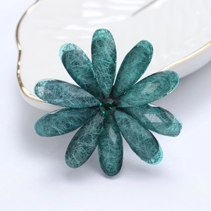 Macro shot of dark green flower brooch with silk textures on a gold-rimmed white plate