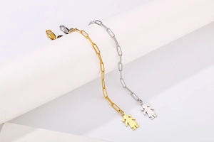 Détail de bracelets chaîne trombone en or et argent avec pendentif petite fille