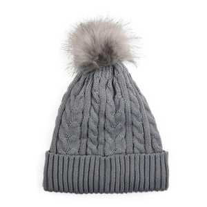 Gros plan du motif en maille torsadée et du pompon en fourrure sur le bonnet d'hiver