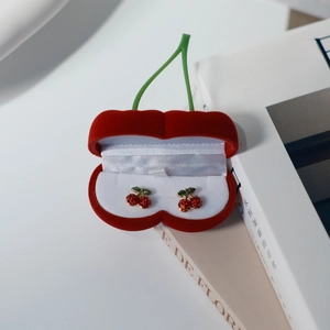 Detalle del joyero de cereza en terciopelo rojo con pendientes de botón de cereza