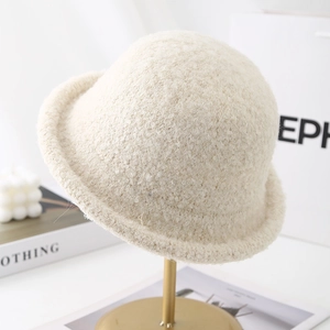 Detail of a creamy white plush winter bucket hat displayed on a premium metal rack