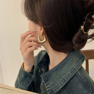 Boucles d'oreilles créoles dorées en U minimalistes avec finition métal poli sur un modèle